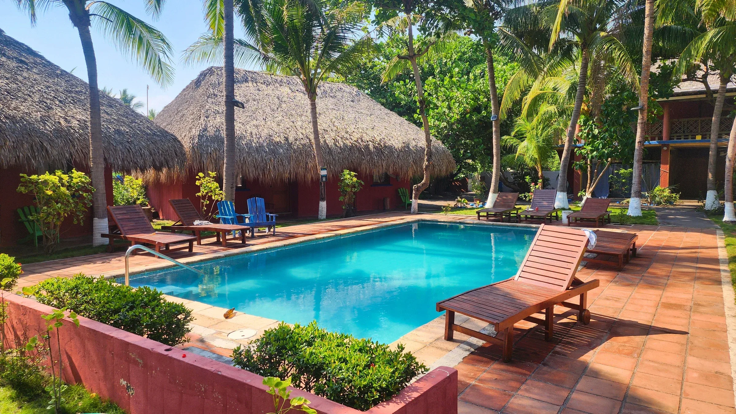 Piscina y edificios de techo de palma rodeados de vegetación en Hotel Dulce y Salado